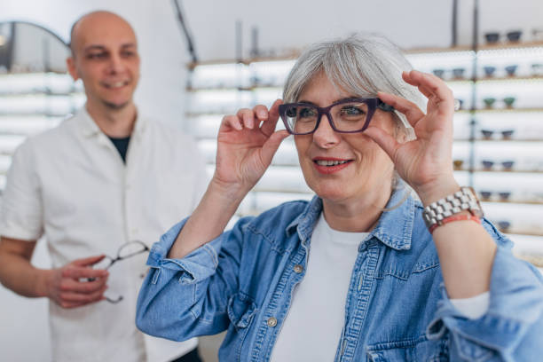 istock Woman adjusting new glasses with store display behind. 2159657480