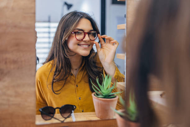 istock Woman adjusting red glasses while smiling in store 2159657529