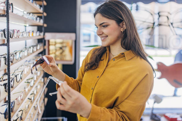 istock Woman in mustard blouse selects glasses from display 2159657915