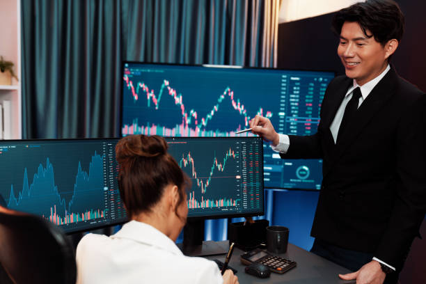 istock Smiling traders pointing to dynamic stock exchange screen at night. Infobahn. 2159660053