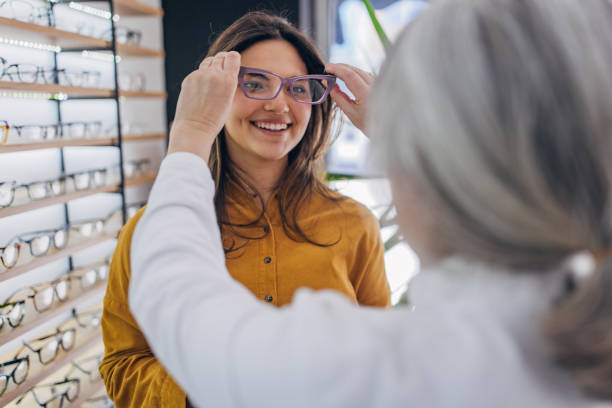 istock Optician fitting eyeglasses on smiling woman 2159664530