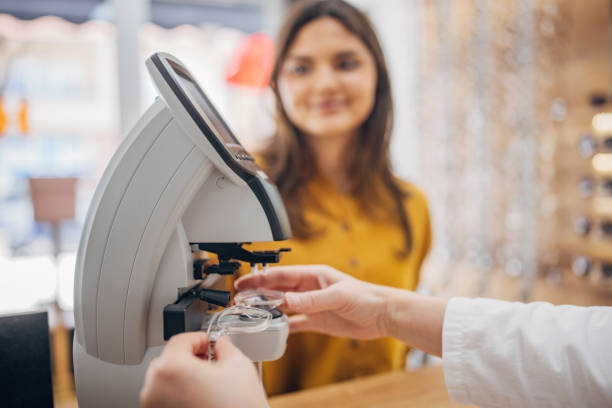 Optician handling lenses with customer in background