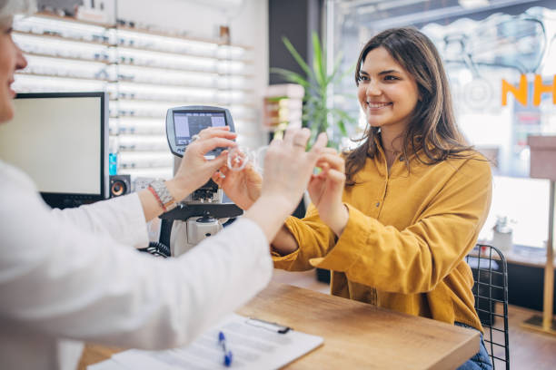 istock Optician hands new eyeglasses to smiling customer 2159664635
