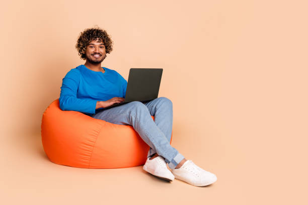 istock Photo of handsome nice guy wear trendy blue clothes sit pouf work empty space isolated on beige color background 2159666952