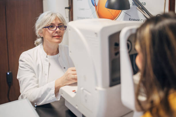 istock Optometrist with gray hair operates eye exam equipment. 2159667256