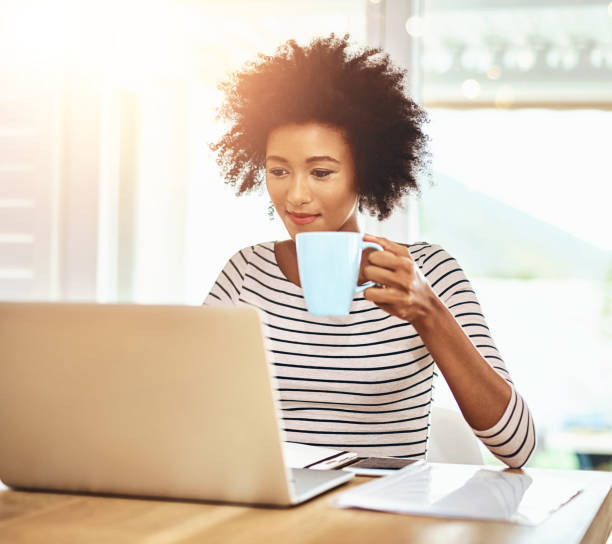 istock Woman, laptop and coffee with remote work from home with reading, documentation and copywriting job in morning. African writer, person and computer with tea cup for editing, planning and creativity 2159674802