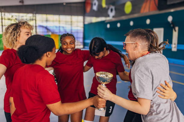 istock Victorious team and coach cheering with trophy in gym 2159674980