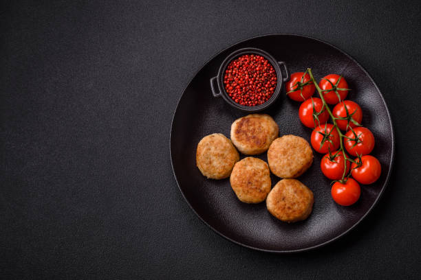 Delicious fresh fried minced fish cutlets with spices and herbs on a dark concrete background
