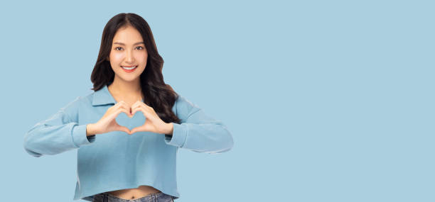 istock Smiling Woman in Blue Making Heart Gesture 2159678492
