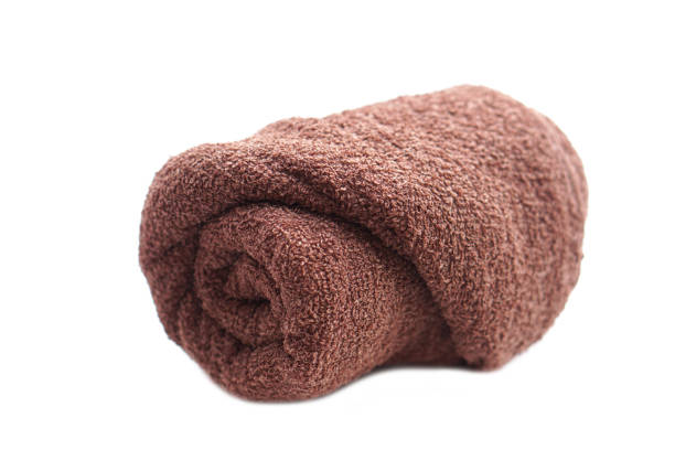 Rolled  brown towel isolated on white background. Concept, clothes in daily life using. Towel for bathing, showering or spa massage.