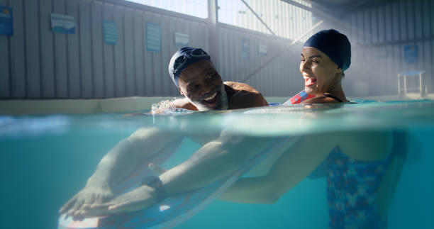 istock Man, swimming coaching and happiness in water for learning, workout or paddle stroke for wellness. Cardio, exercise and male person with coach in pool, training with professional for development 2159682776