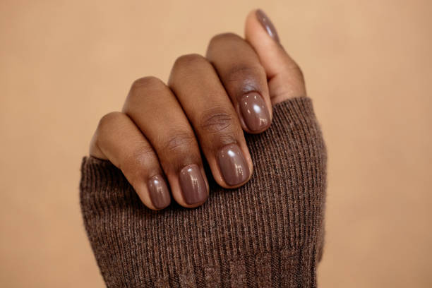 Chocolatey Brown Casual Manicure Close up shot of simple nail design in rich brown shade for autumn complementing outfit on beige background chocolate fingers stock pictures, royalty-free photos & images