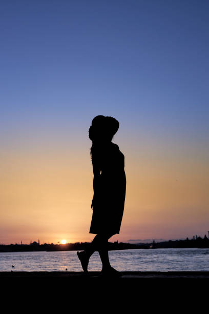 istock lady in hat silhouette with sea and sunset sky 2159687557
