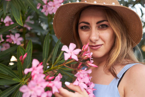 istock lady with hat smelling pink flowers 2159687698