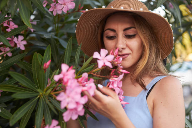 istock lady with hat smelling pink flowers 2159687706