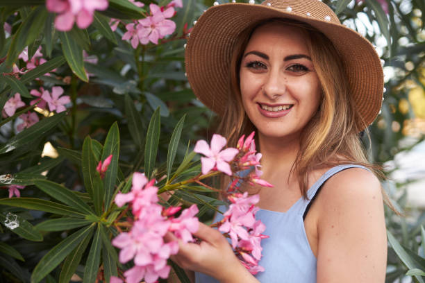 istock lady with hat smelling pink flowers 2159687718