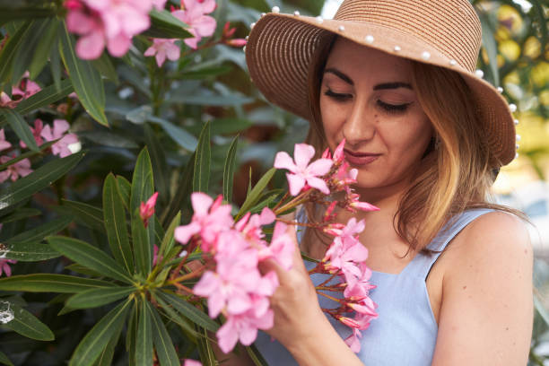 istock lady with hat smelling pink flowers 2159687796