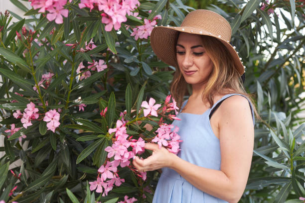 istock lady with hat smelling pink flowers 2159687816