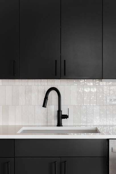 istock A kitchen faucet detail with black cabinets and vertical subway tile backsplash. 2159691264