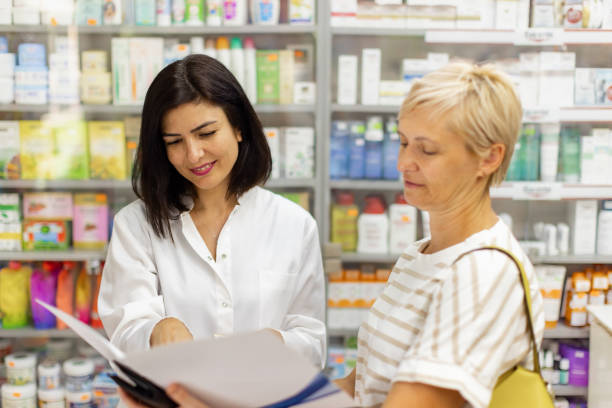 istock Young female Caucasian pharmacist talking with an customer at the 2159692020