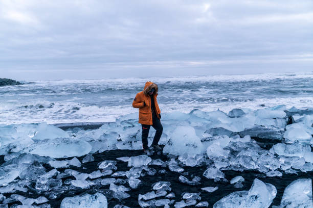 istock Person Exploring Ice Beach with Ocean Waves Crashing Nearby 2159692776