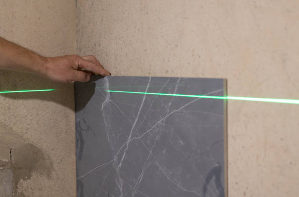 istock Builder is measures the repair lines for laying tiles using a laser level with green beams. Close up. 2159694167