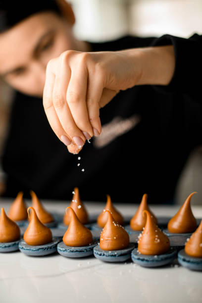 istock Culinary girl sprinkles with powdered sugar a macarons with whipped cream 2159694214
