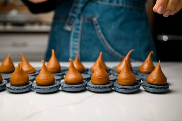 istock Macarons with whipped cream on a white table and pastry chef in a jeans 2159694237