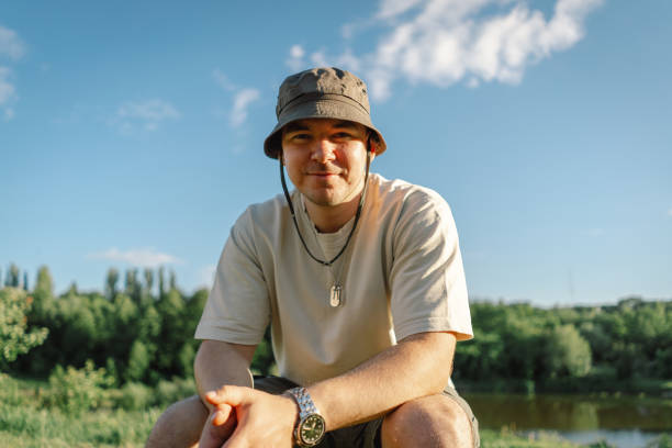 Portrait of a man enjoy the nature by the fire in sunny weather. Hiking camp with a bonfire in the forest. Tourist on recreation outside. Campsite lifestyle