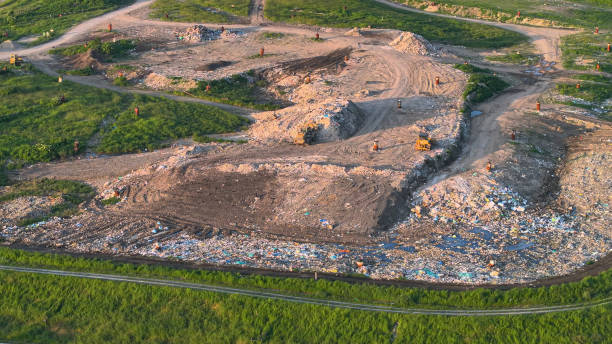 AERIAL: Municipal garbage dump with waste burial and partially restored landfill