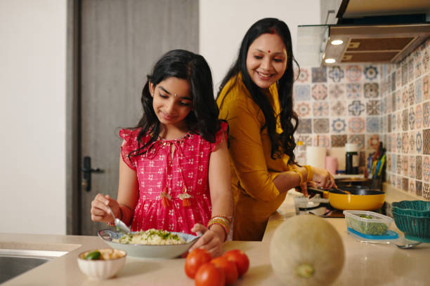 Daughter Helping Her Mom In The Kitchen Daughter helping her mom in the kitchen to cook dinner for family family dinners and cooking stock pictures, royalty-free photos & images