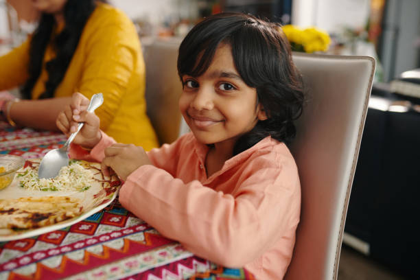 Indian Boy Having Dinner With Family Portrait of Indian boy smiling at camera while having dinner with his family indian dinner stock pictures, royalty-free photos & images