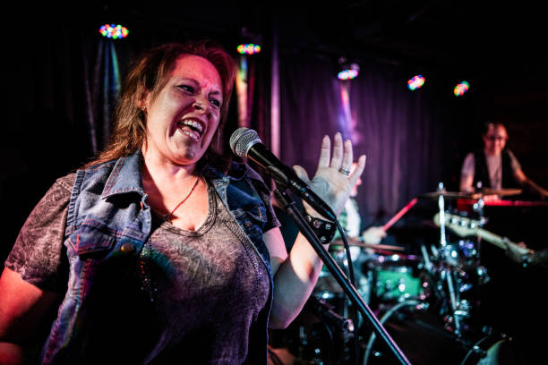 Mature woman singing with rock band on stage