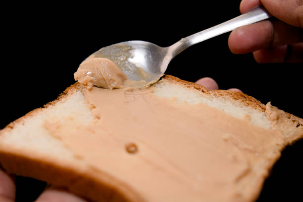 istock Peanut butter spread on a slice of bread with a spoon 2159708097