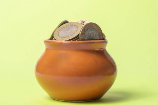 istock Coins in a clay pot on a green background. Money saving concept. 2159710928