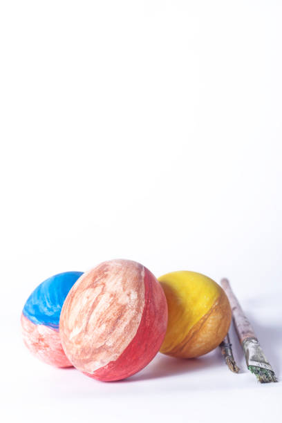 Colorful painted Easter eggs and paint brush on white background with copy space