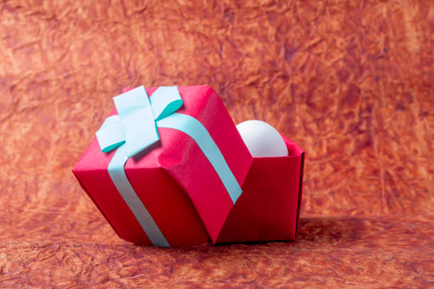 Pink gift box with pink bow on pink background. \nBox in the center. Monochromatic Simple Object Tabletop. Copy space.