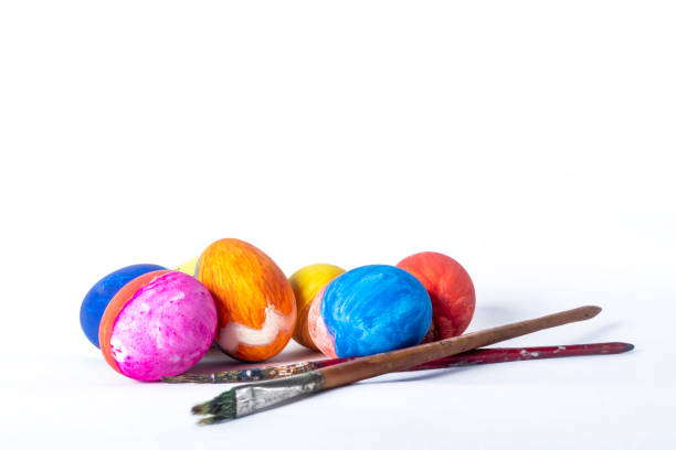 Colorful painted Easter eggs and paint brush on white background with copy space