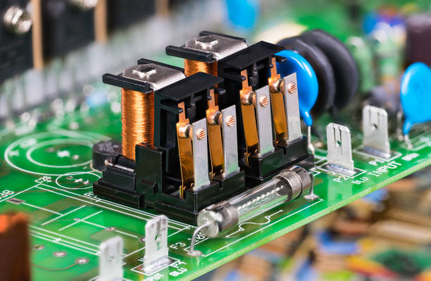 Electronic components as electromagnetic relays or glass electric fuse on green PCB stock photo