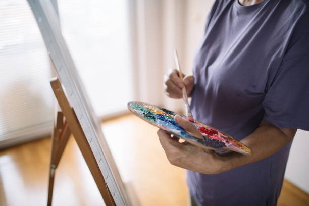 Midsection of mature woman mixing colors for her painting.