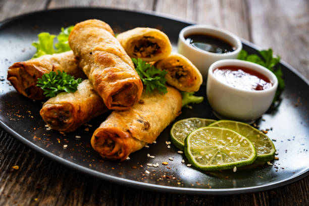 istock Spring rolls filled with meat and vegetables served with soy sauce on wooden table 2159718002