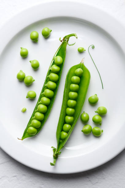 istock Green sugar snap peas on white plate close up 2159719955