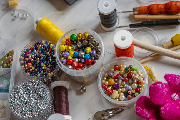 Creating Christmas ornaments. Handcraft artist workspace. Laptop, colorful beads, felt, tools, scissors, needles, thread spools, glue, containers, pliers, wire. Creative chaos concept. Flat lay.