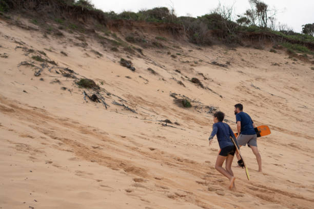 istock People with skateboard climbing the dune 2159728394