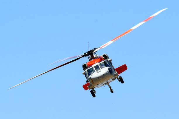 istock Red and white helicopter flying in a clear blue sky 2159734292