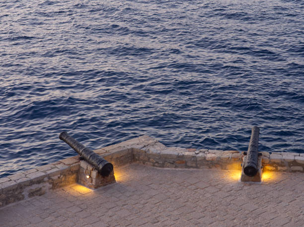 Hydra cobblestone fortified cannons and sea high angle view at blue hour. Saronic Gulf, Greece
