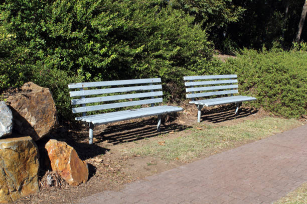 istock Two blue benches seats with green plants, rocks and a footpath 2159742267