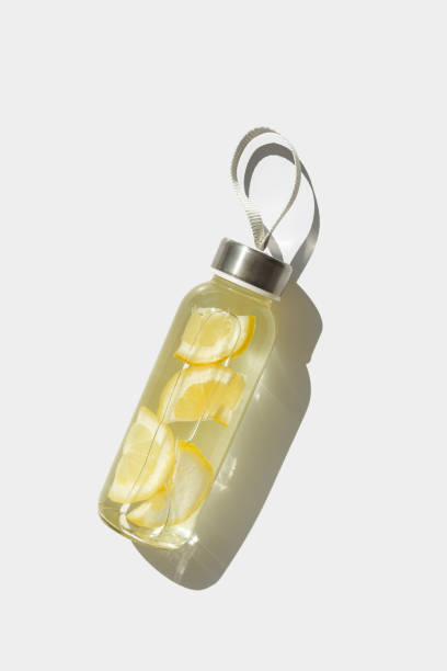 istock Top view glass bottle, lemon water drink detox, sunlight shadow, natural light, white background, copyspace. Infused water with slices citrus fruit. Minimal Aesthetic photo with fresh drink 2159747244