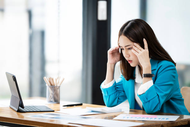 istock Stressed woman with head in hand sitting at desk office, feels uncomfortable working. 2159754595