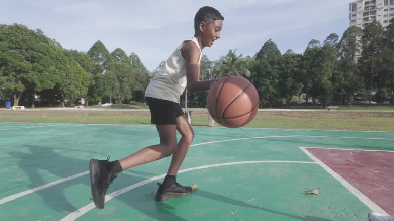Asian Indian father with amputee artificial leg playing basketball with his son weekend morning